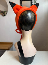 Load image into Gallery viewer, Mannequin head wearing an orange fox fleece headband with decorative mushrooms and plants in the background.