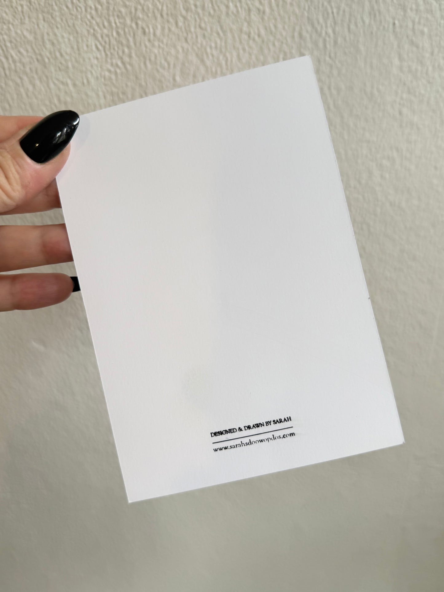 Card with a red devil design held by a hand against a white background