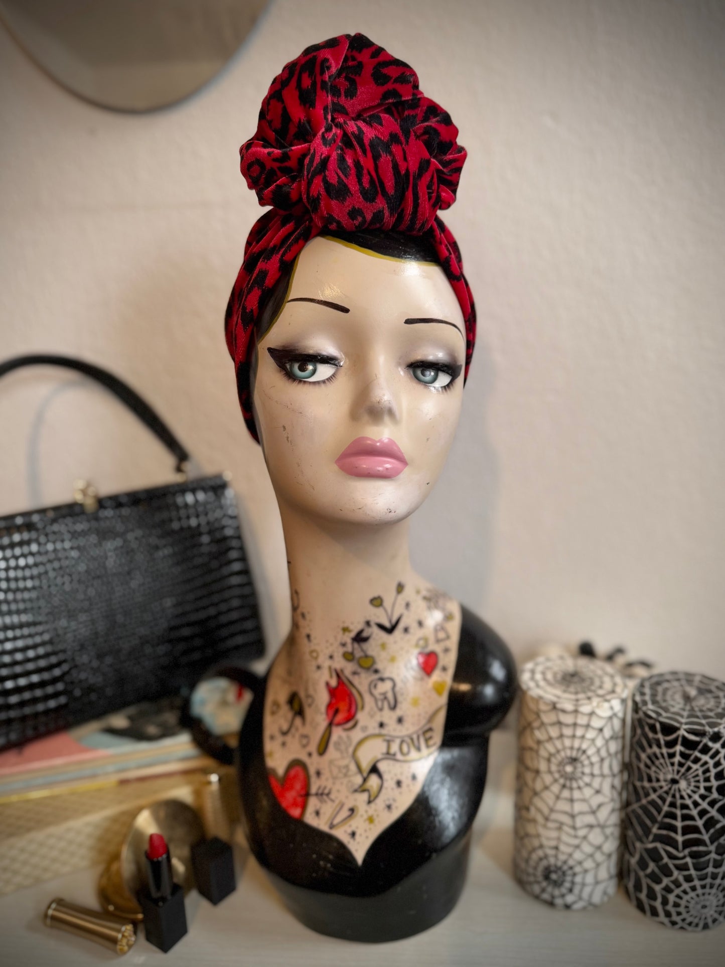 Red leopard print headband on a display head with tattoos