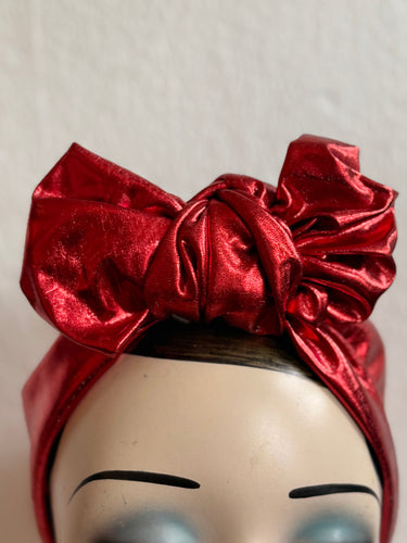 Red metallic headband on a mannequin head with a neutral background