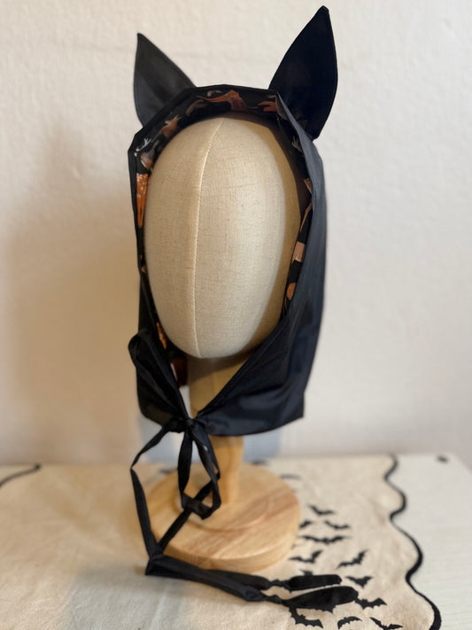 Black rain bonnet with gothic bat ears on a mannequin head against a neutral background