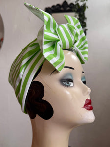Mannequin head wearing a halloween themed  green and white striped headscarf with a large bow.
