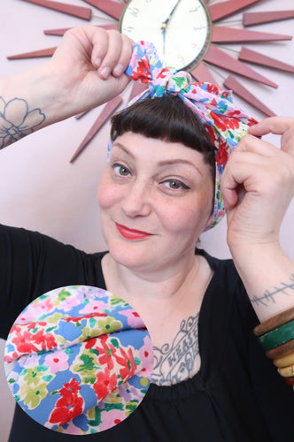 Woman tying a blue floral 1940s handmade vintage headscarf