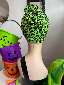 Green leopard print headscarf on a mannequin with Halloween-themed buckets in the background.