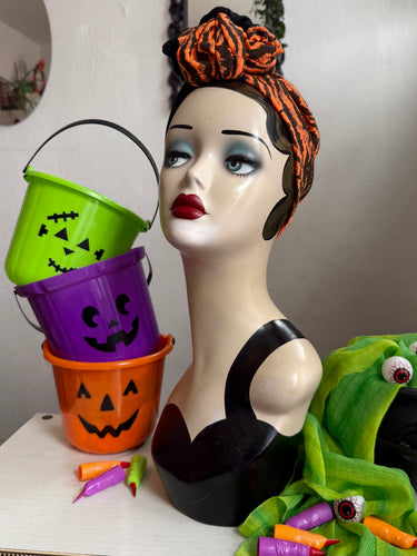 Mannequin head with Halloween-themed decorations including buckets and a witch hat.