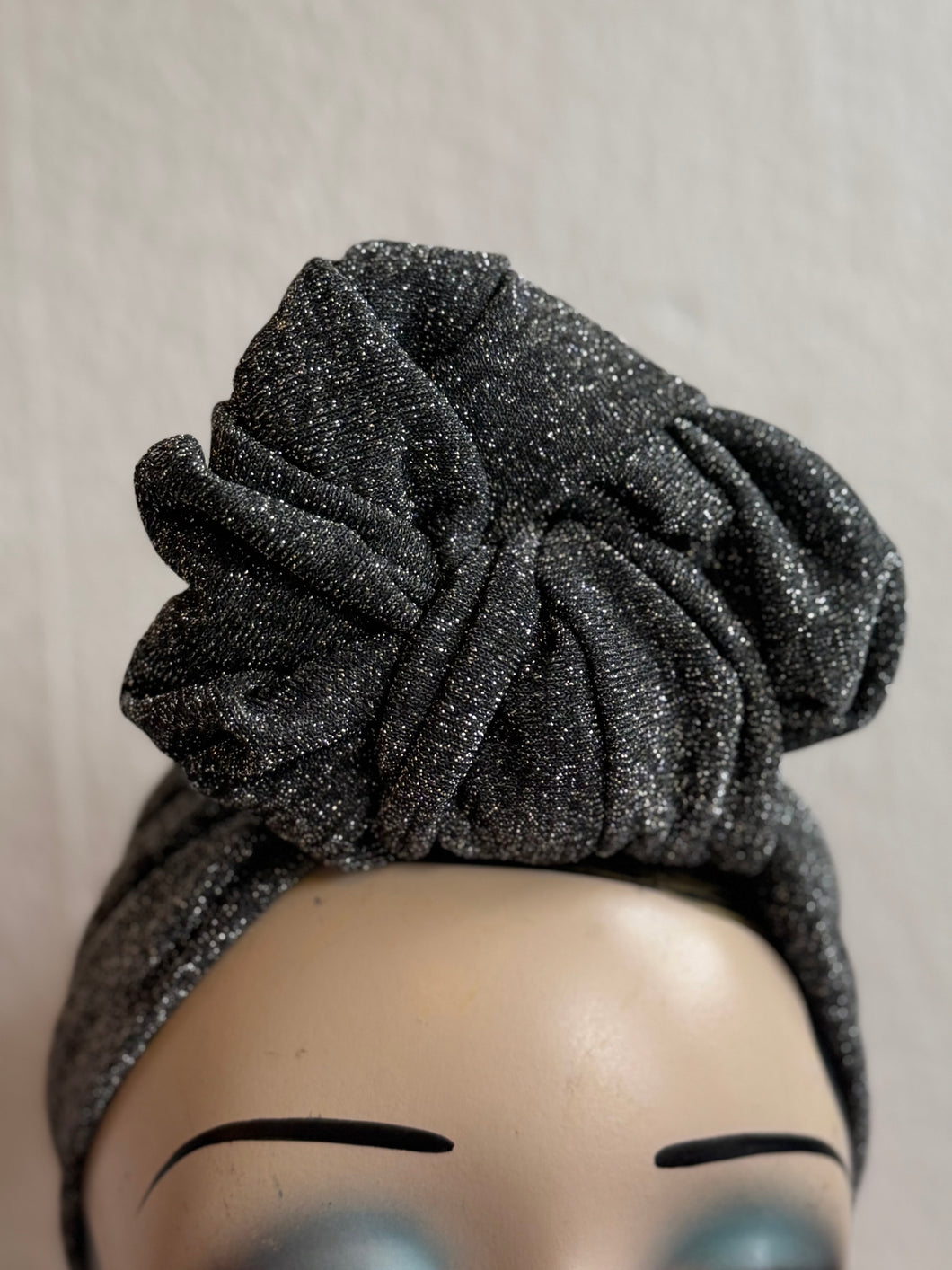Black glittery headband on a mannequin head against a neutral background