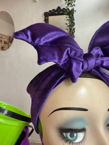 Mannequin head with purple bat shaped headband against a neutral background
