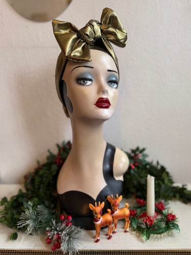 Mannequin head with gold headscarf, Christmas decorations, and deer figurines in background