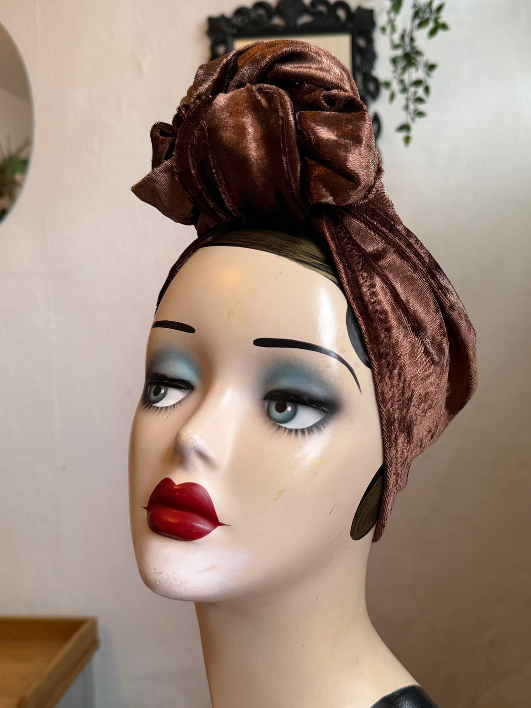 Mannequin head wearing a brown velvet turban with a neutral background