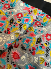 Load image into Gallery viewer, Floral and skeleton patterned fabric with colorful flowers and black bones on a gray background.