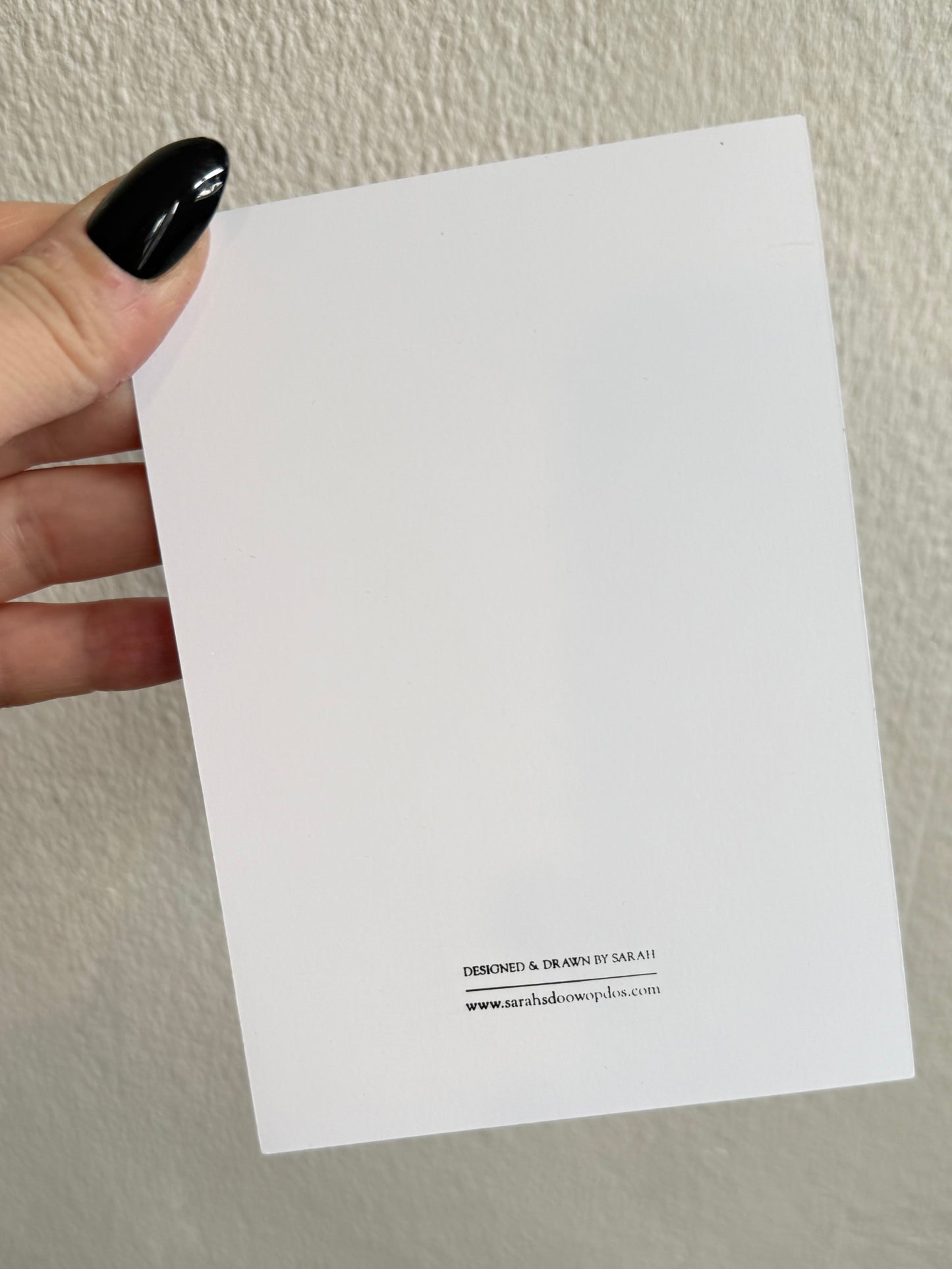Card with a leopard print hat design held by a hand against a white background