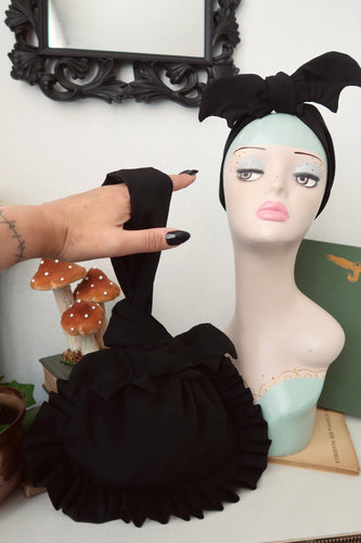 Hand with gothic nails holding a black ruffle bag