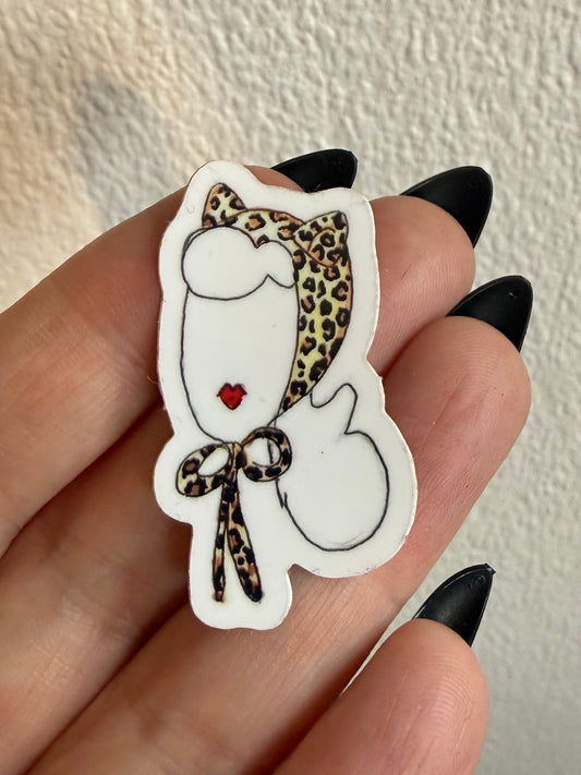 Sticker of a cat wearing a leopard print headscarf held between fingers against a neutral background