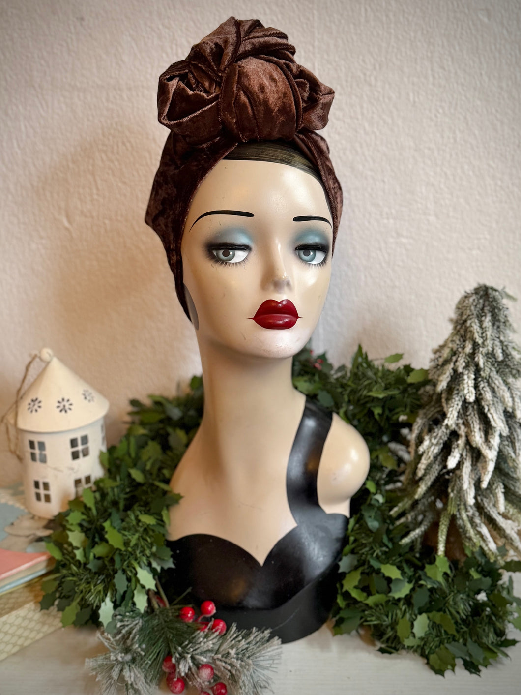 Mannequin head with a brown velvet headscarf in a decorative setting with Christmas decor