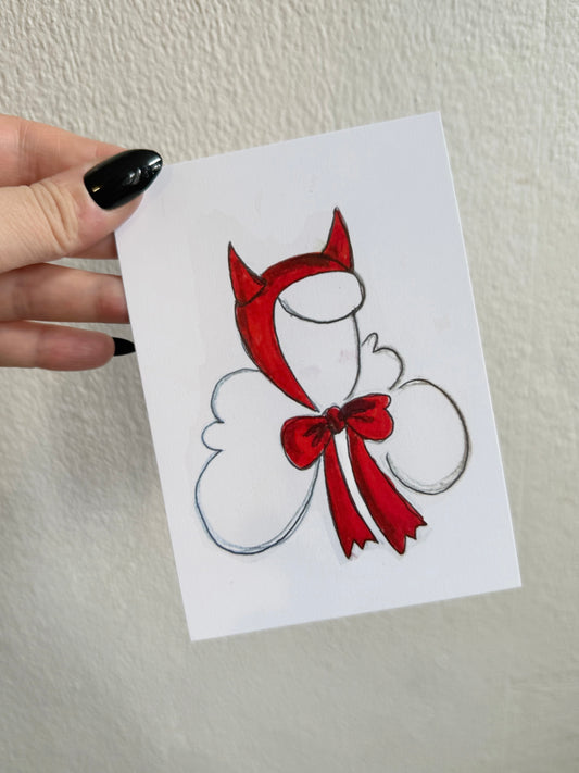 Card with a red devil design held by a hand against a white background