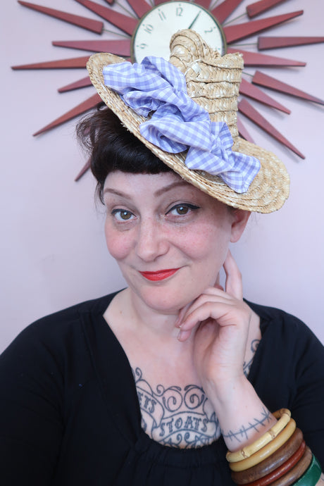 Woman wears a dramatic 1940s vintage style straw hat with lilac gingham ribbon 