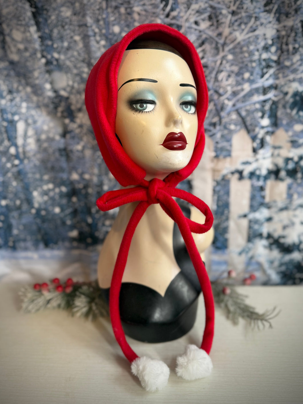 Mannequin head wearing a red hood with a snowy background