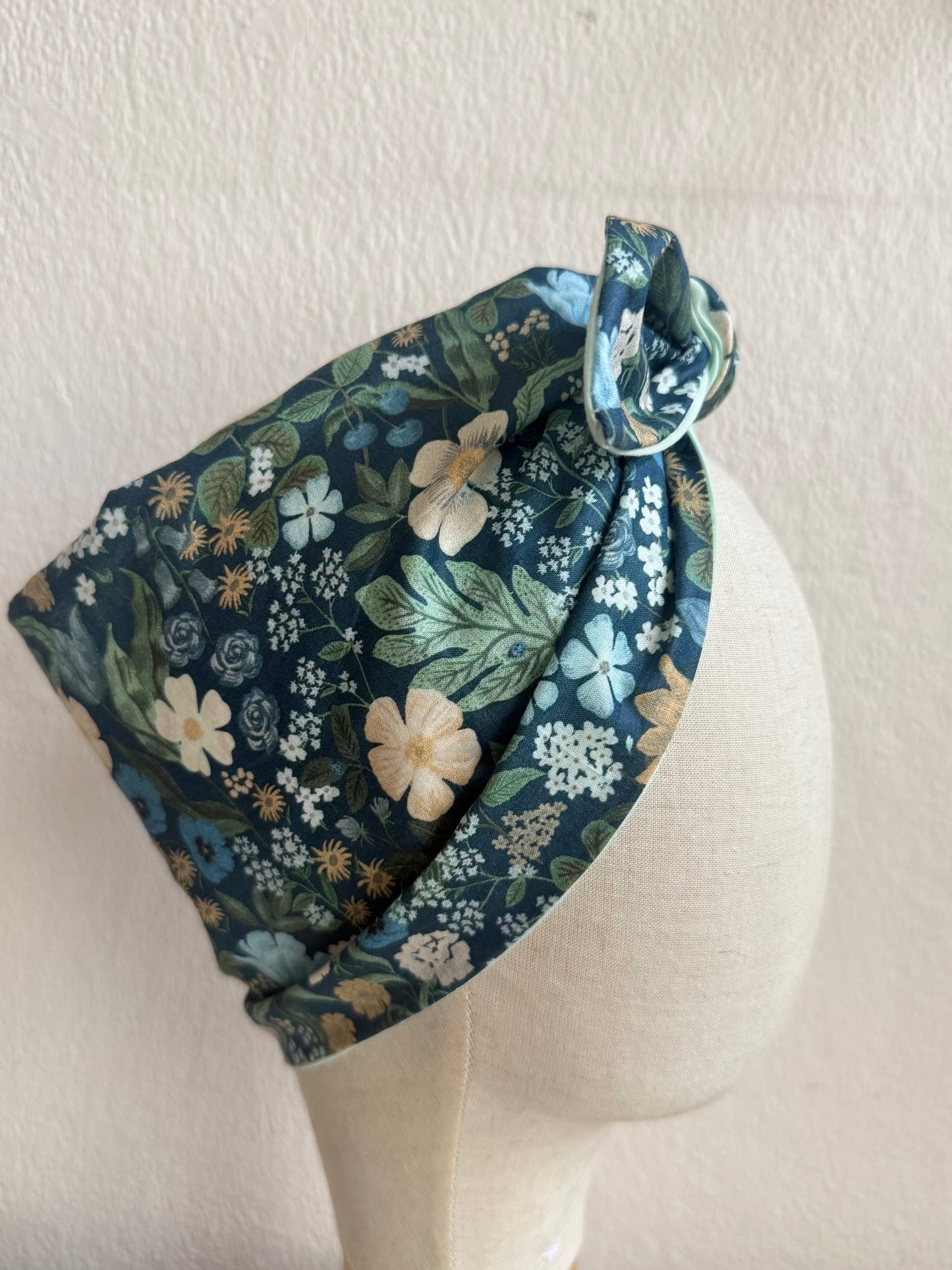 Floral headband on a mannequin head against a plain background