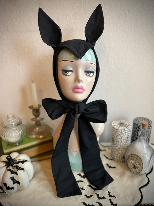 Mannequin head wearing a black gothic bat headband on a decorative background.