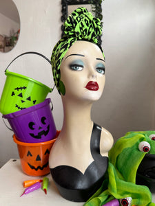 Mannequin head with Halloween-themed decorations including buckets and a green headscarf.
