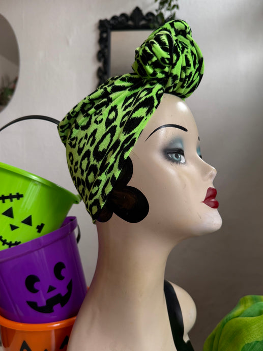 Mannequin head with a green leopard print headband against a neutral background