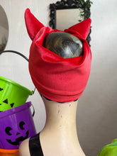 Load image into Gallery viewer, Red hood with cat ears on a mannequin head, with Halloween buckets in the background.