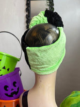 Load image into Gallery viewer, Mannequin head with a green headband and black hair, surrounded by Halloween-themed buckets.