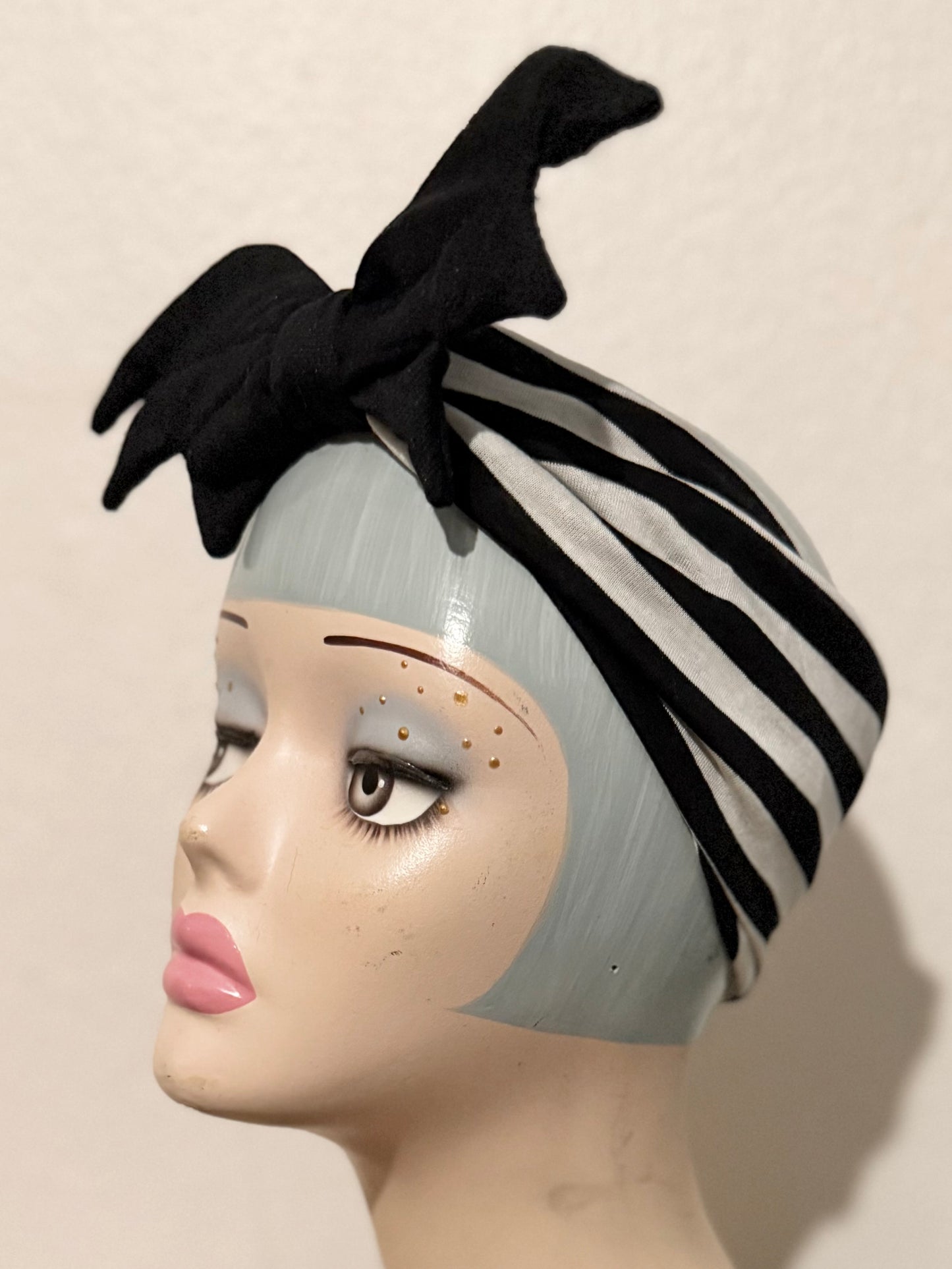 Mannequin head with a black bat halloween headband on a neutral background