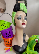 Load image into Gallery viewer, Mannequin head with green hair and makeup, surrounded by Halloween-themed buckets and decorations.