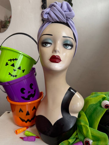 Mannequin head with Halloween makeup and accessories, including buckets and a green creature.