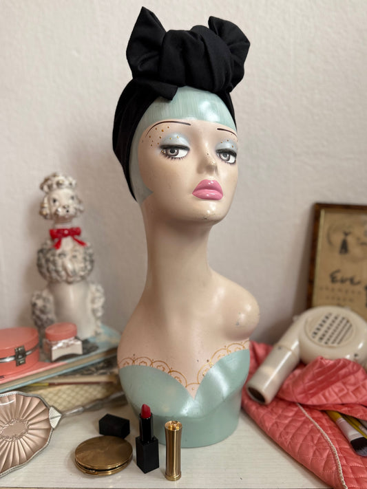 Display head wearing a glamorous black vintage handmade turban on a dressing table