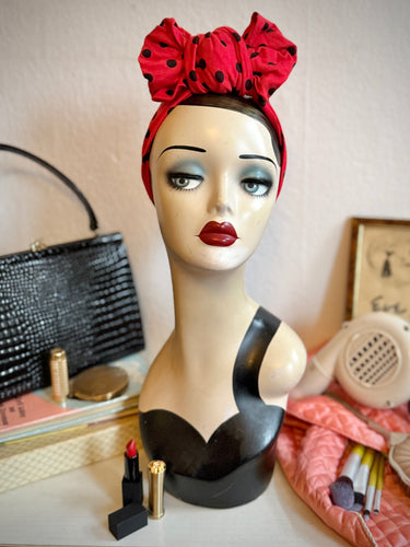 Mannequin head with red polka dot headband on a table.