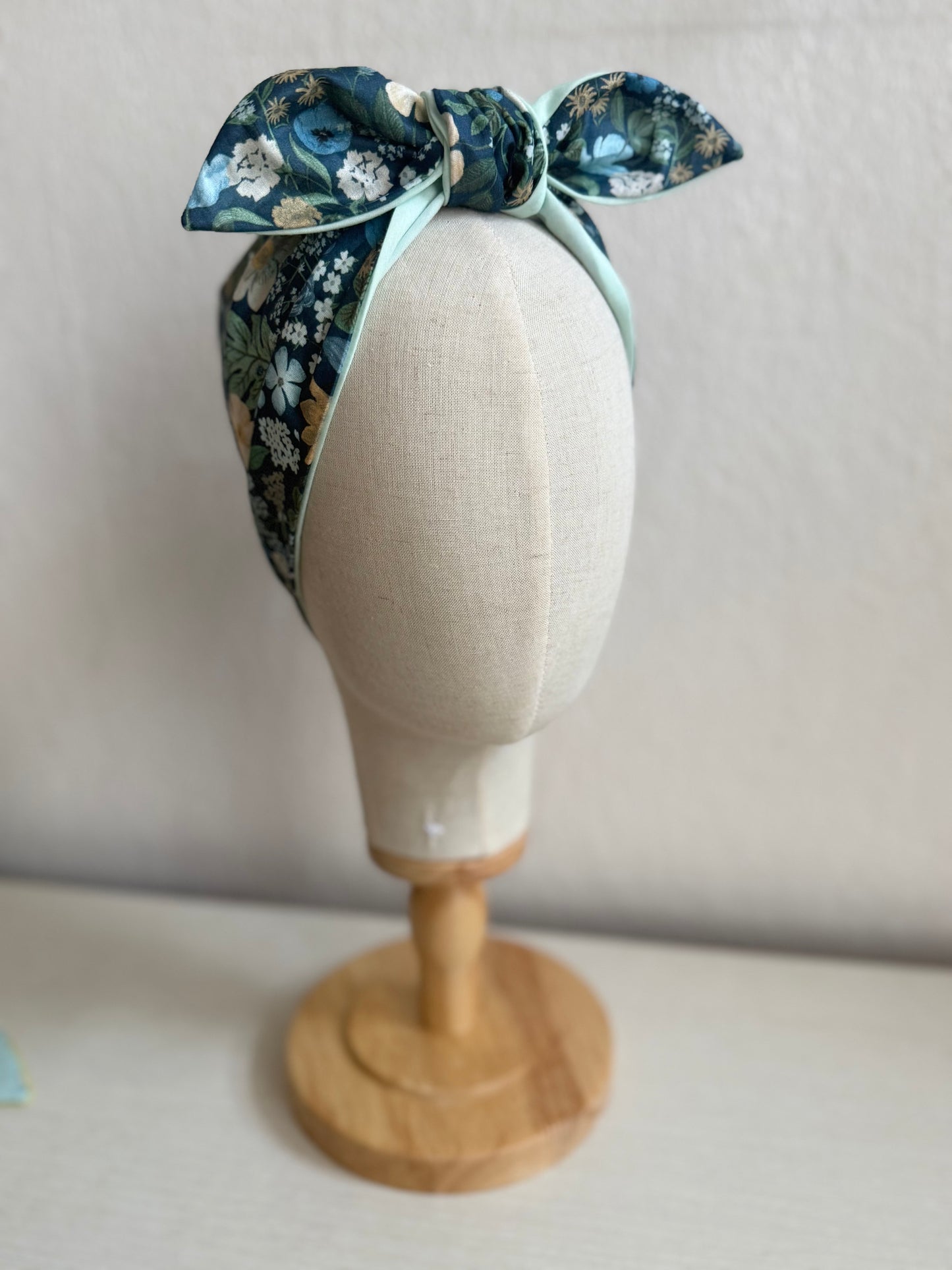 Floral headband on a mannequin head against a plain background