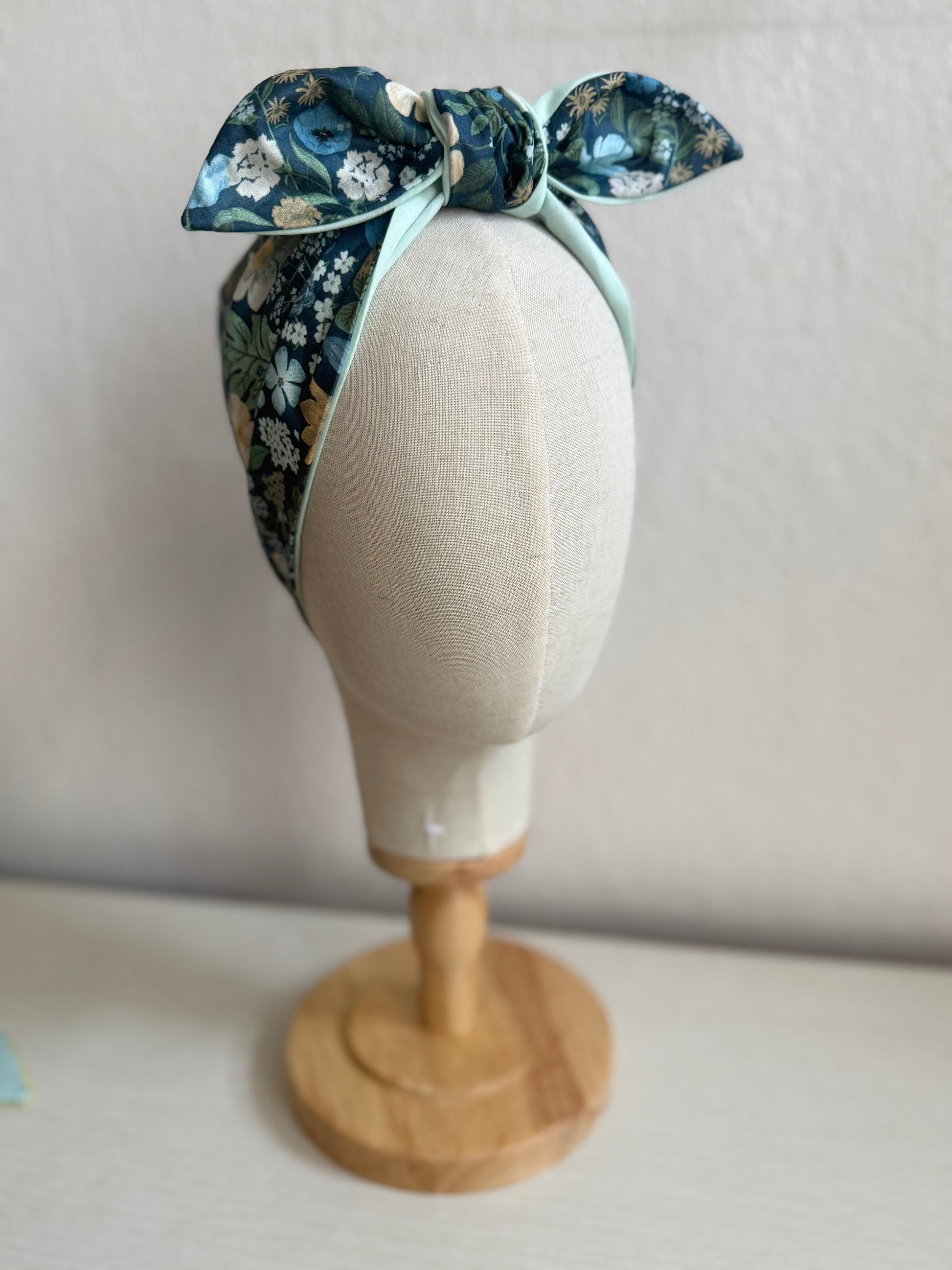 Floral headband on a mannequin head against a plain background