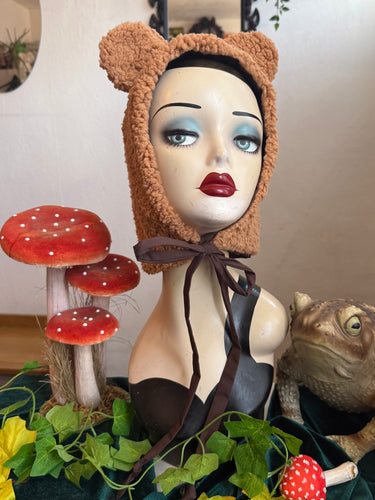 Mannequin head wearing a brown bear hat.