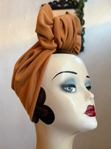 Mannequin head wearing a mustard headscarf with a blurred background