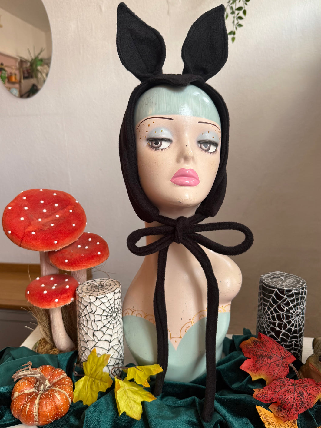 Mannequin head wearing a black bat ear headband with autumn decorations.
