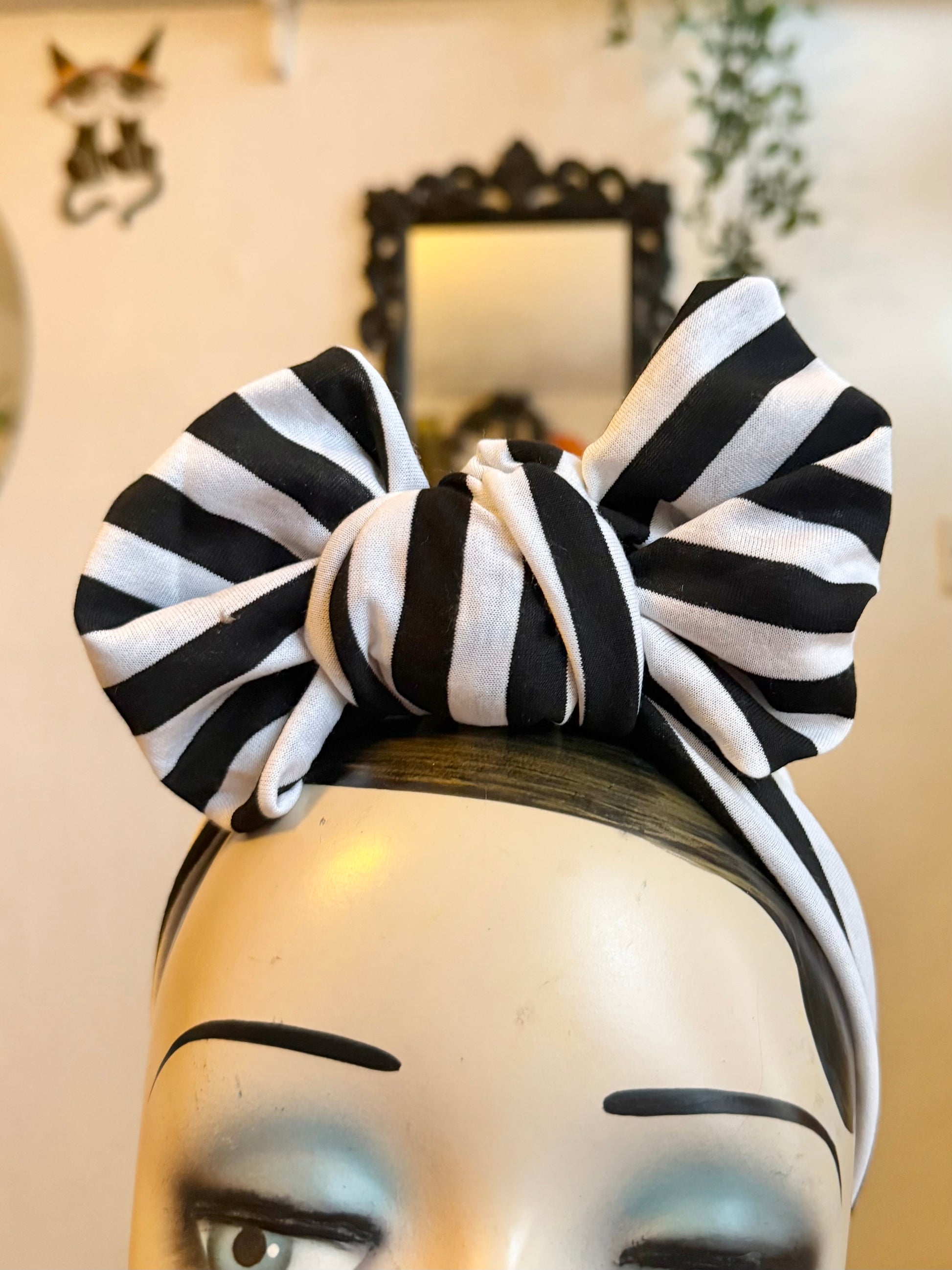 Mannequin head with black and white striped headband on a plain background