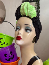 Load image into Gallery viewer, Mannequin head with Halloween makeup and green hair bow, next to colorful buckets.