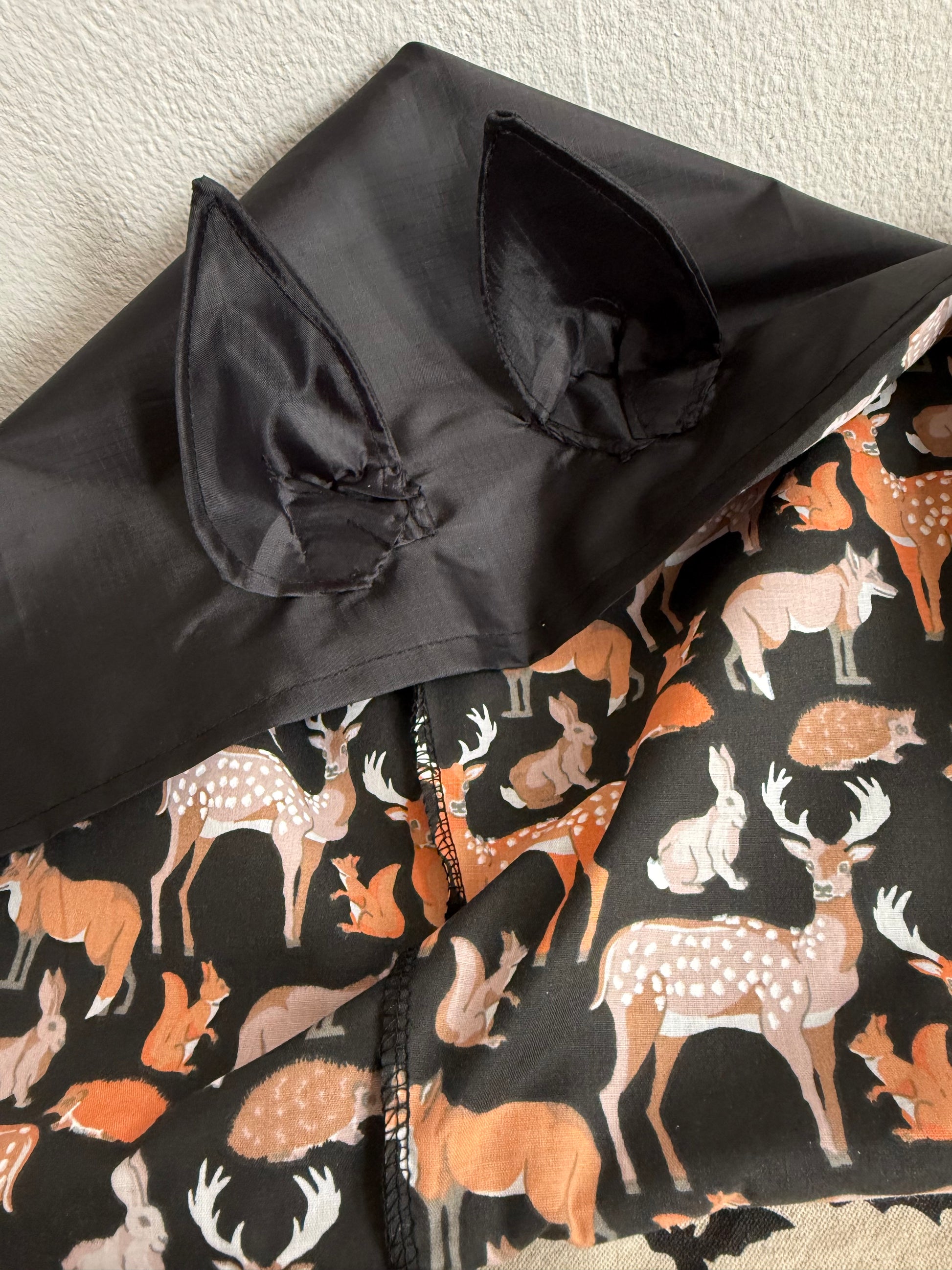 Black rain bonnet with gothic bat ears on a mannequin head against a neutral background