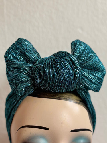 Teal glittery headband on a mannequin head against a plain background