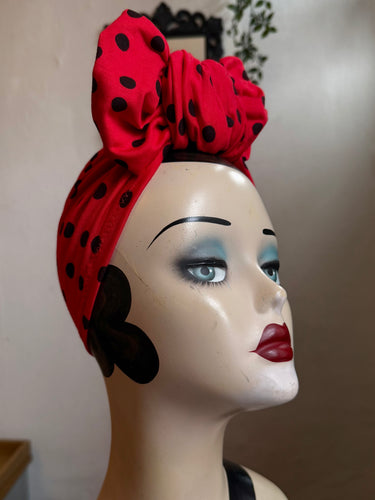 Mannequin head wearing a red polka dot turban with a neutral background