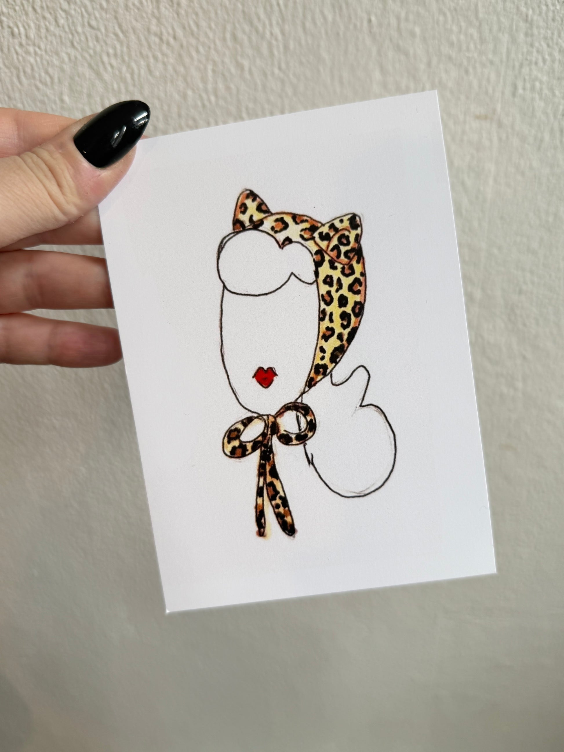 Card with a leopard print hat design held by a hand against a white background