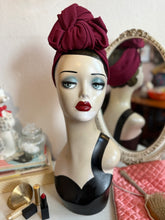 Load image into Gallery viewer, Mannequin head with a burgundy turban and makeup items on a table.