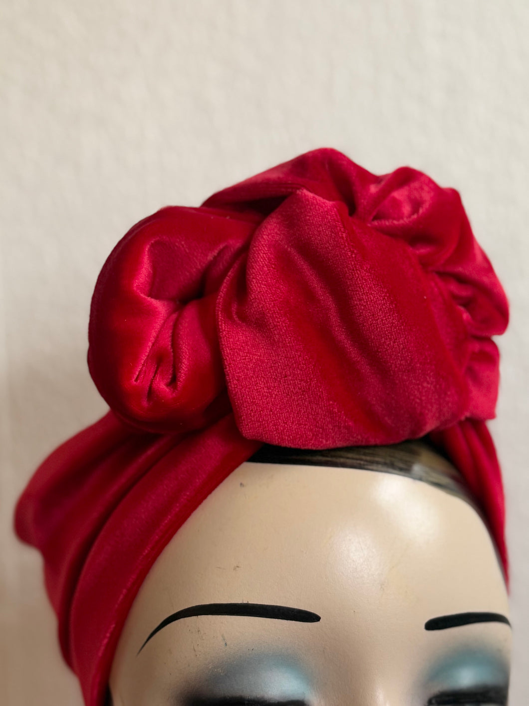 Red velvet headscarf on a mannequin head against a plain background
