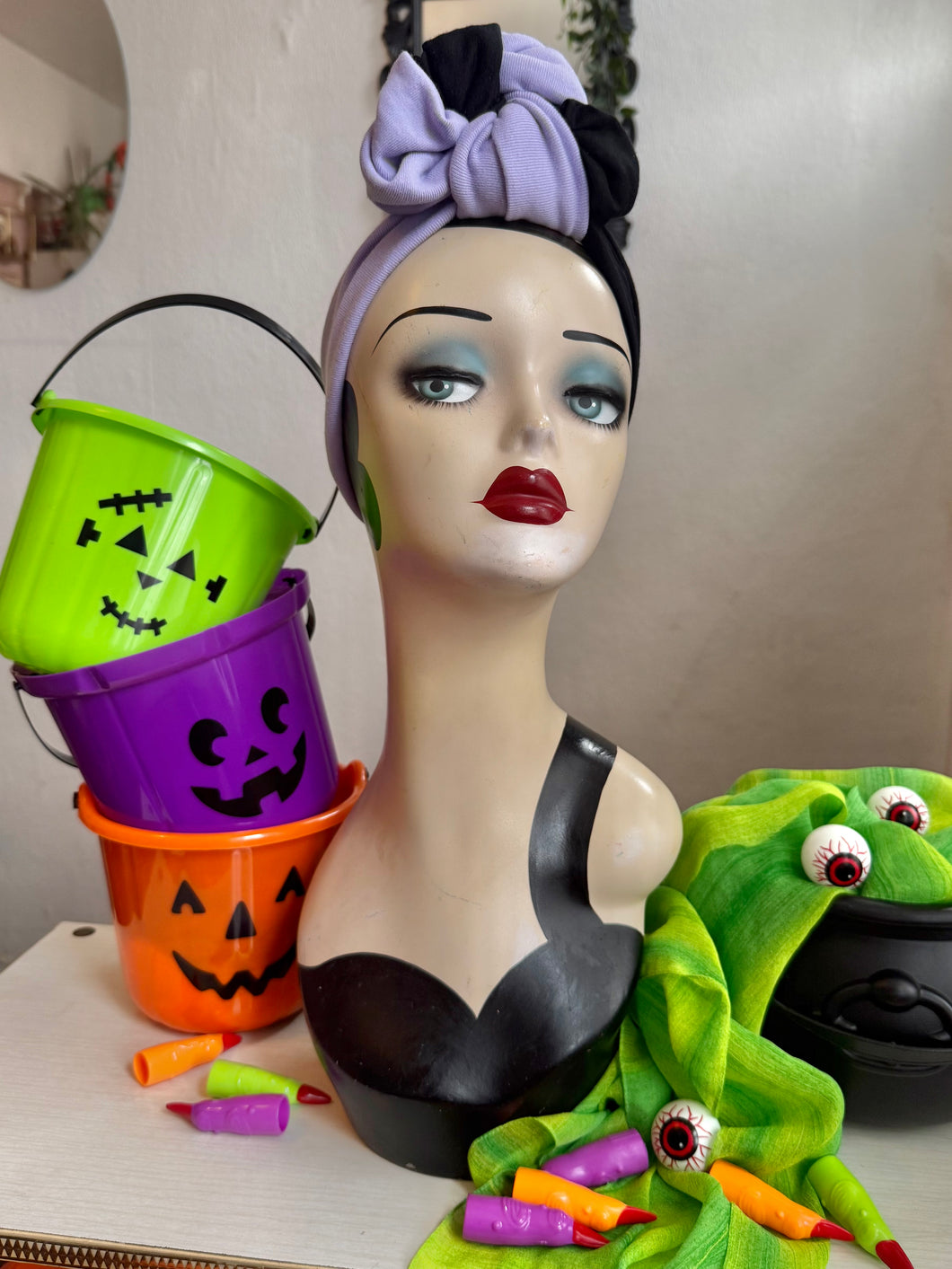 Mannequin head with Halloween-themed decorations including buckets and a frog figure.