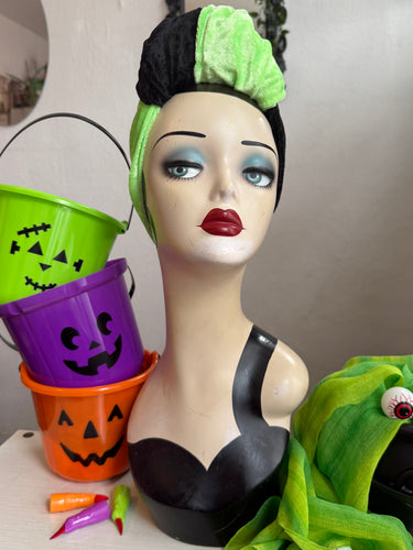 Mannequin head with green hair and makeup, surrounded by Halloween-themed items.