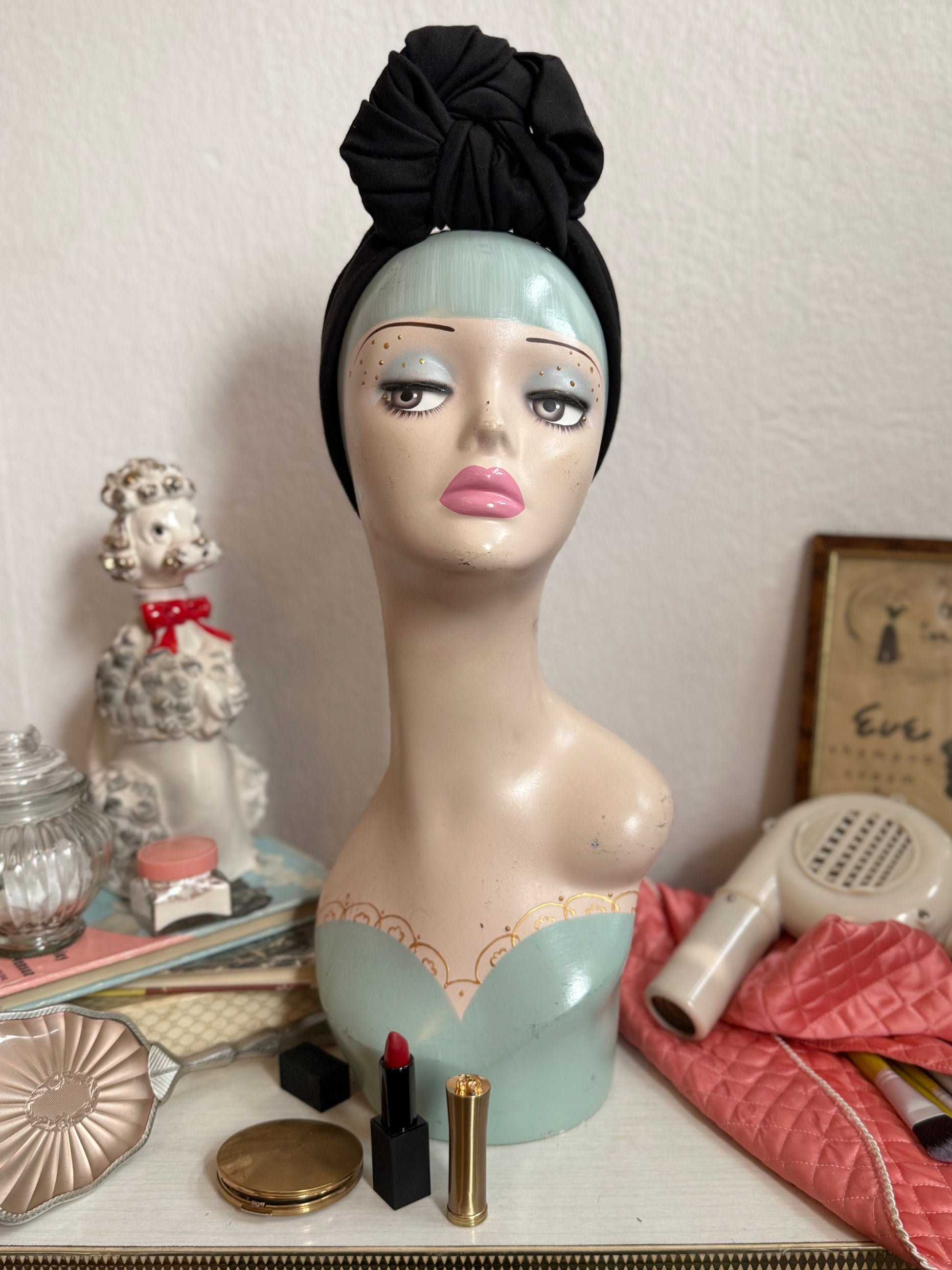 Vintage display head wearing a glamorous black handmade headband on a dressing table full of vintage make up