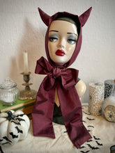 Load image into Gallery viewer, Mannequin head wearing a red devil horns headpiece with a large bow, surrounded by Halloween decorations.