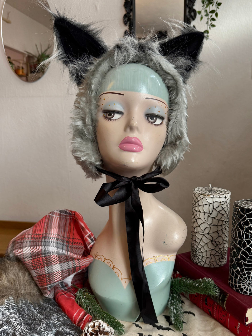 Gray furry werewolf ear headband on a mannequin head with a neutral background